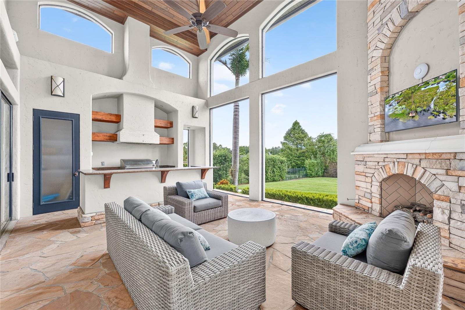 This area of the covered lanai is screened with a remote controlled screen to the covered outdoor dining area and pool. Full summer kitchen with bar. 