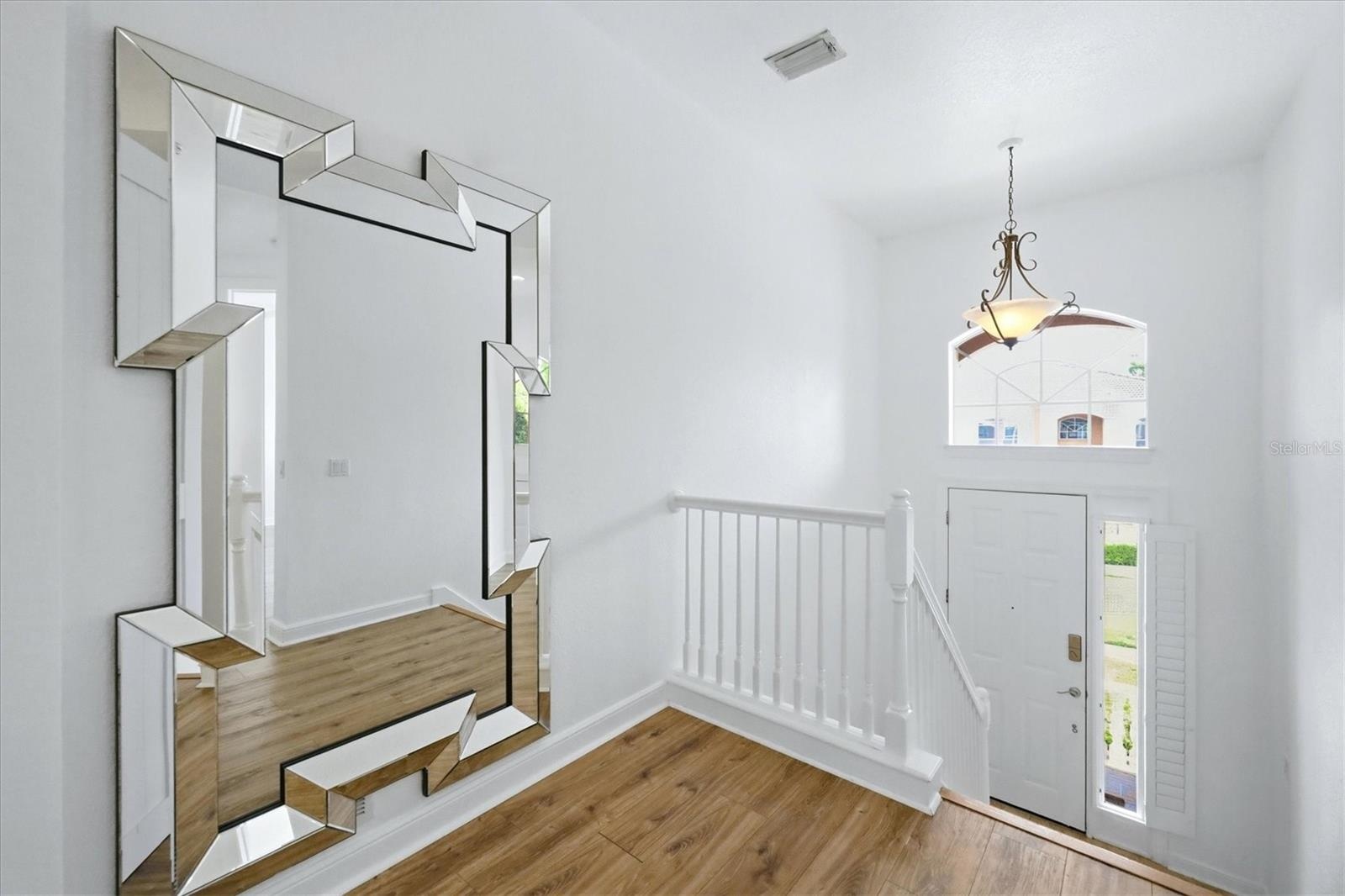 foyer, stairs lead up to main living area, and down to garage and storage closets