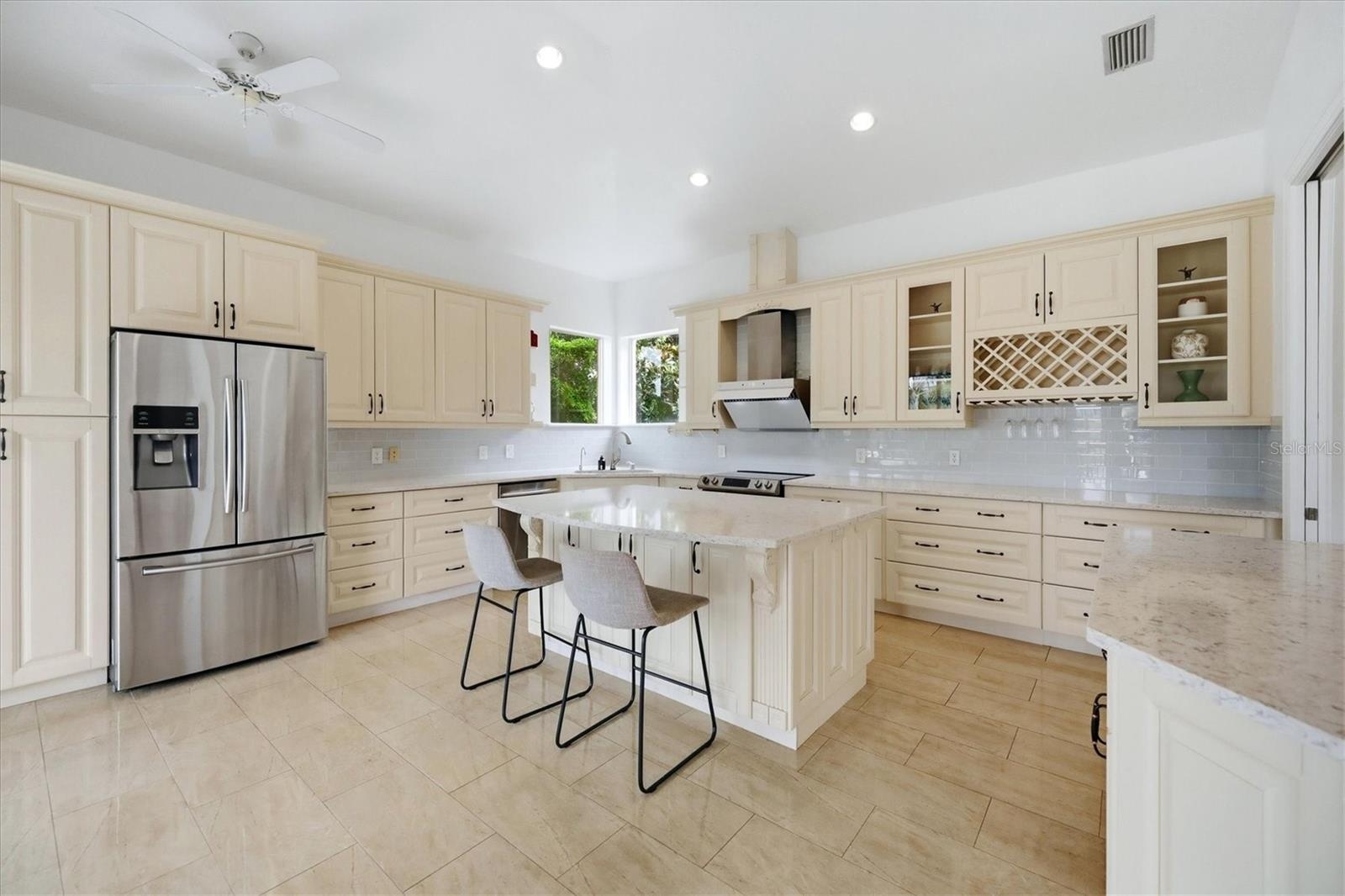 blonde wood cabinets, stainless steel appliances, stone counters, pantry cabinets, eat at island and work desk