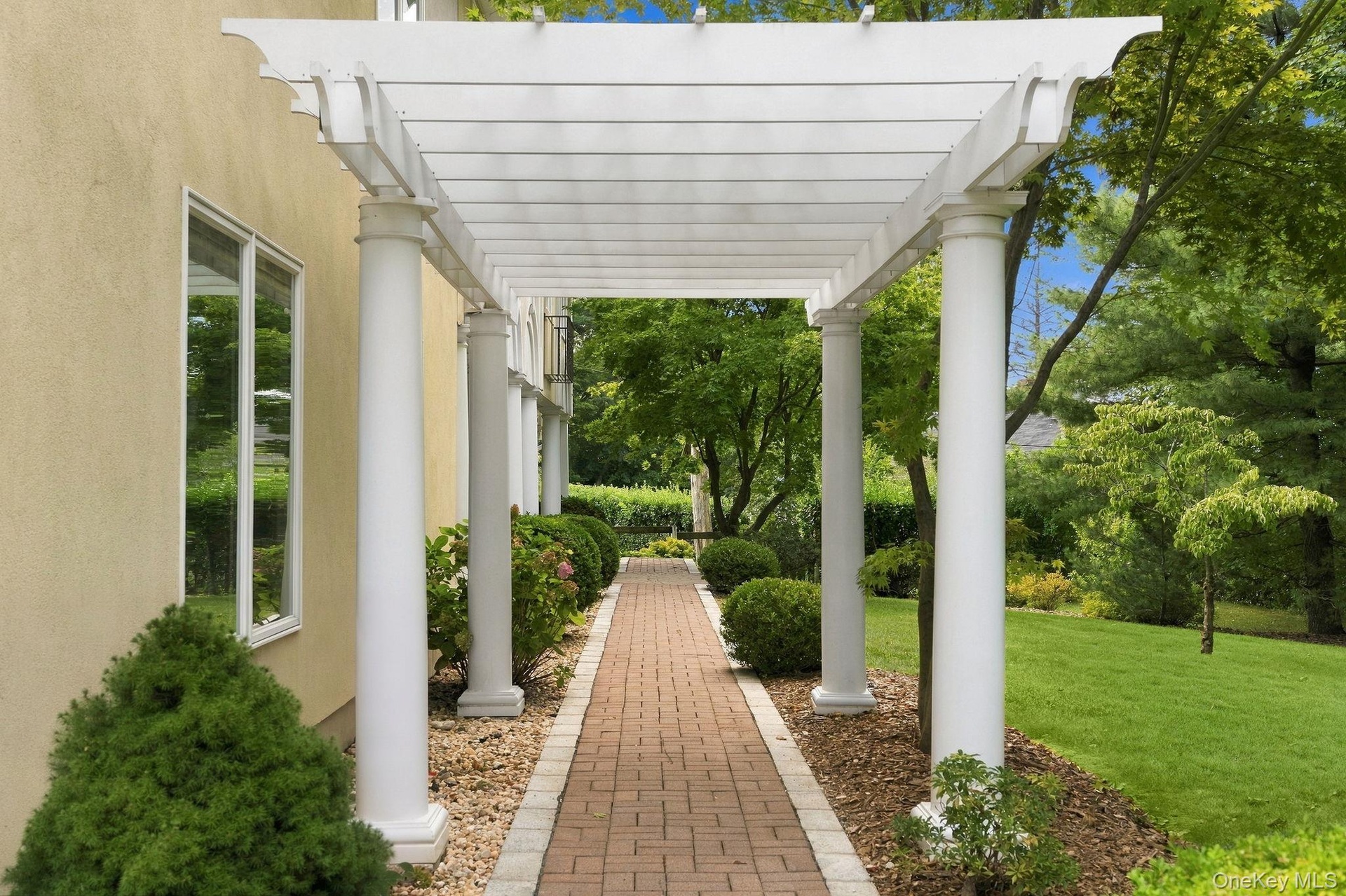 A gracious garden walkway leads beneath an impressive columned portico.