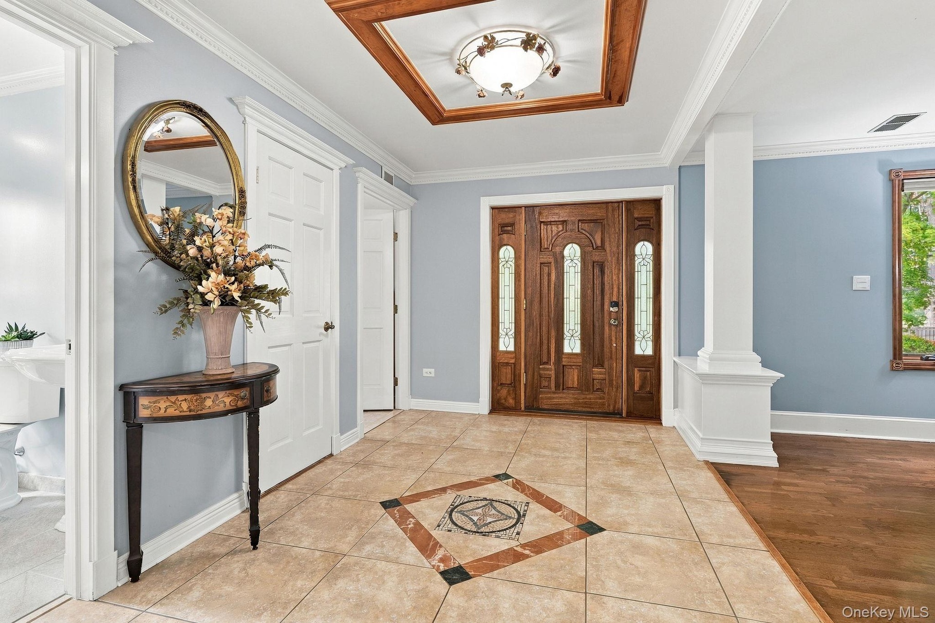 A grand introduction of hardwood floors, architectural columns and dentil molding.