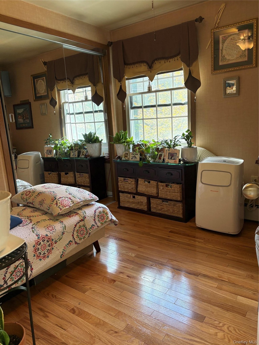 Hardwood flooring, dual windows, built-in shelving, and a mirrored wall