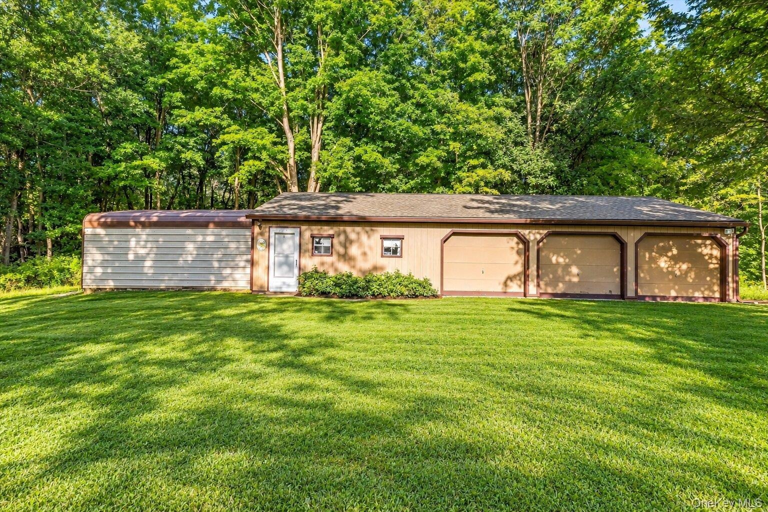 Virtually enhanced exterior view highlighting the detached garage, multiple bays, and spacious surrounding grounds.