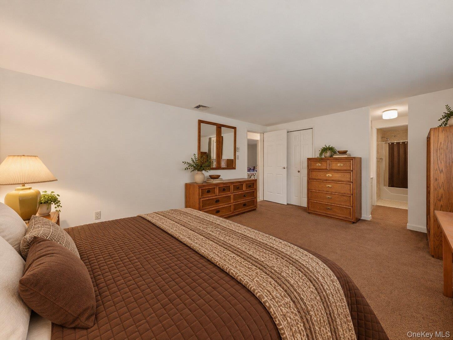 Virtually staged primary bedroom highlighting the generous room size, storage, and convenient connection to the adjoining bathroom.