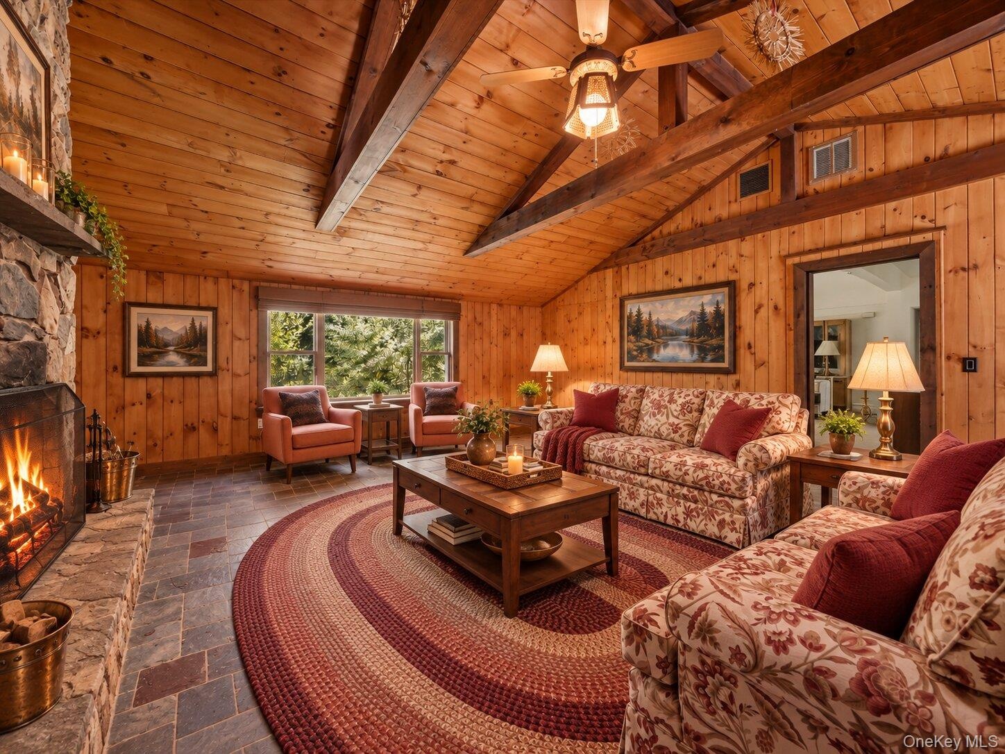 Virtually staged family room highlighting the vaulted wood ceiling, exposed beams, stone fireplace, and generous seating area.
