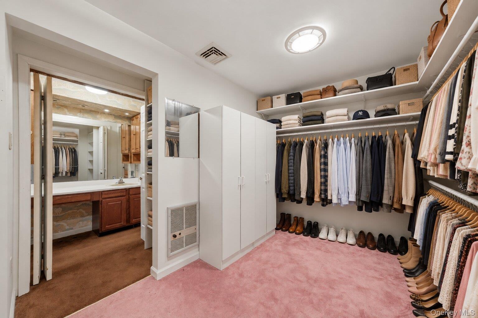 Virtually organized walk-in closet highlighting the extensive hanging space, shelving, and convenient bathroom access.