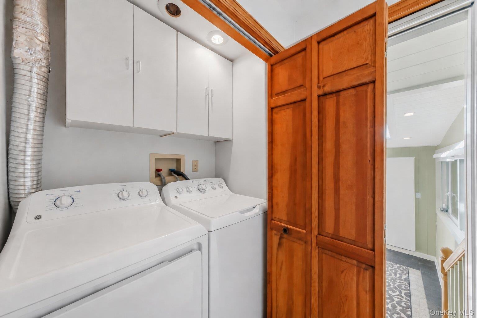 Convenient laundry area with side-by-side washer and dryer, overhead cabinetry, and additional storage.