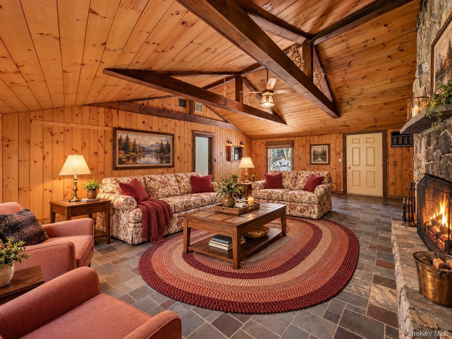 Virtually staged family room showcasing the spacious layout, architectural beams, and impressive stone fireplace.