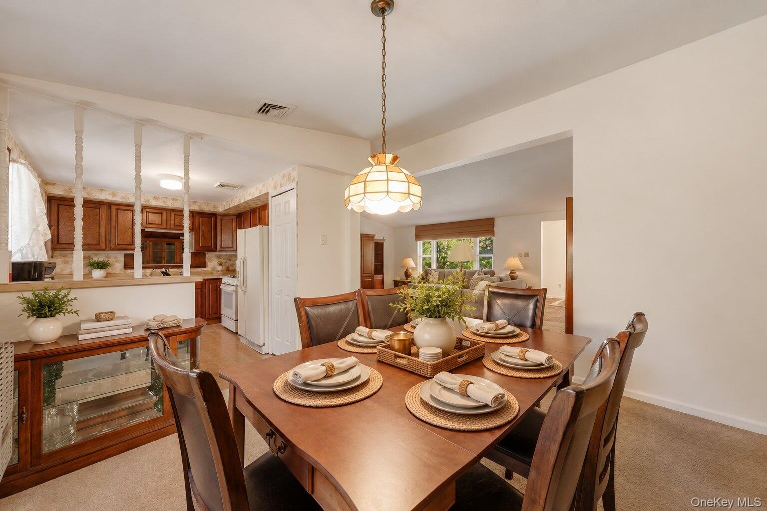 Virtually Staged. Dining area with a classic light fixture, generous table space, and easy flow into the kitchen and living room.
