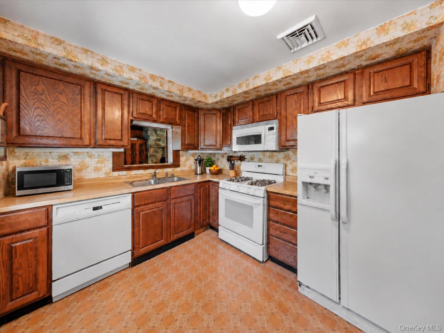 Full kitchen view featuring extensive wood cabinetry, ample counter space, and a practical appliance layout.