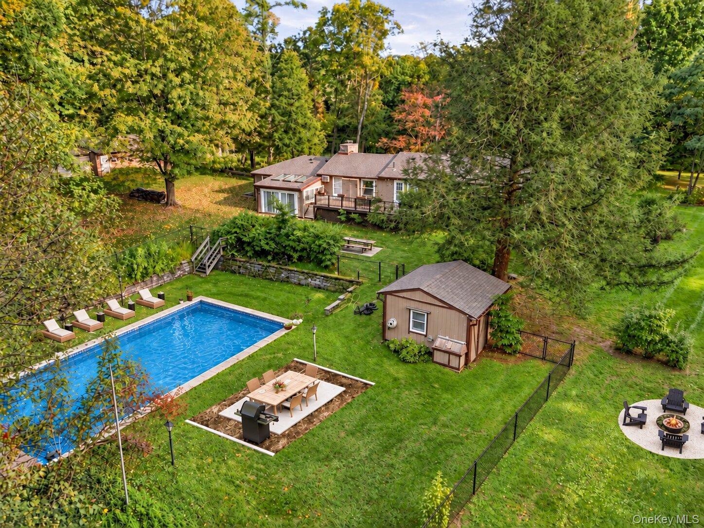 Virtually enhanced aerial view highlighting the pool, entertaining areas, fire pit, and generous backyard setting.