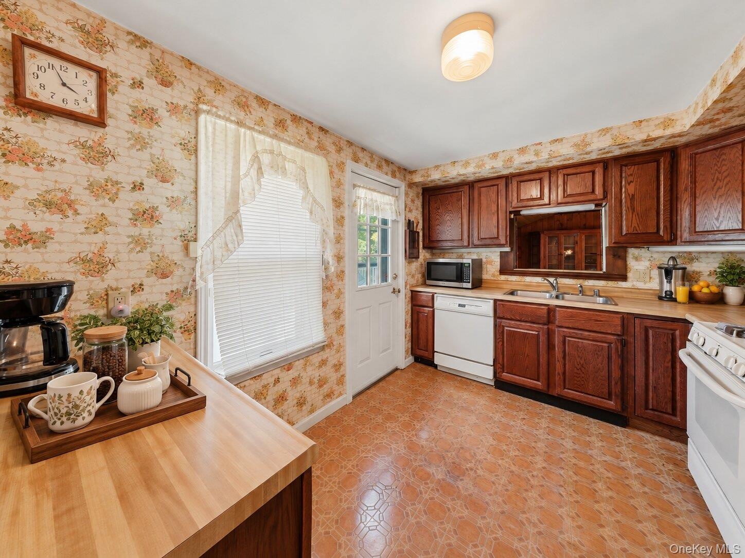 Virtually decluttered kitchen showcasing the generous counter space, cabinetry, and convenient exterior access
