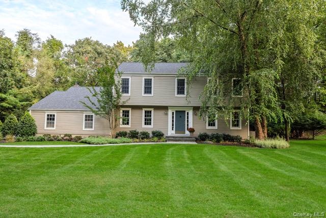 Two-story colonial residence with light tan siding, a dark gray shingle roof, and white-framed windows