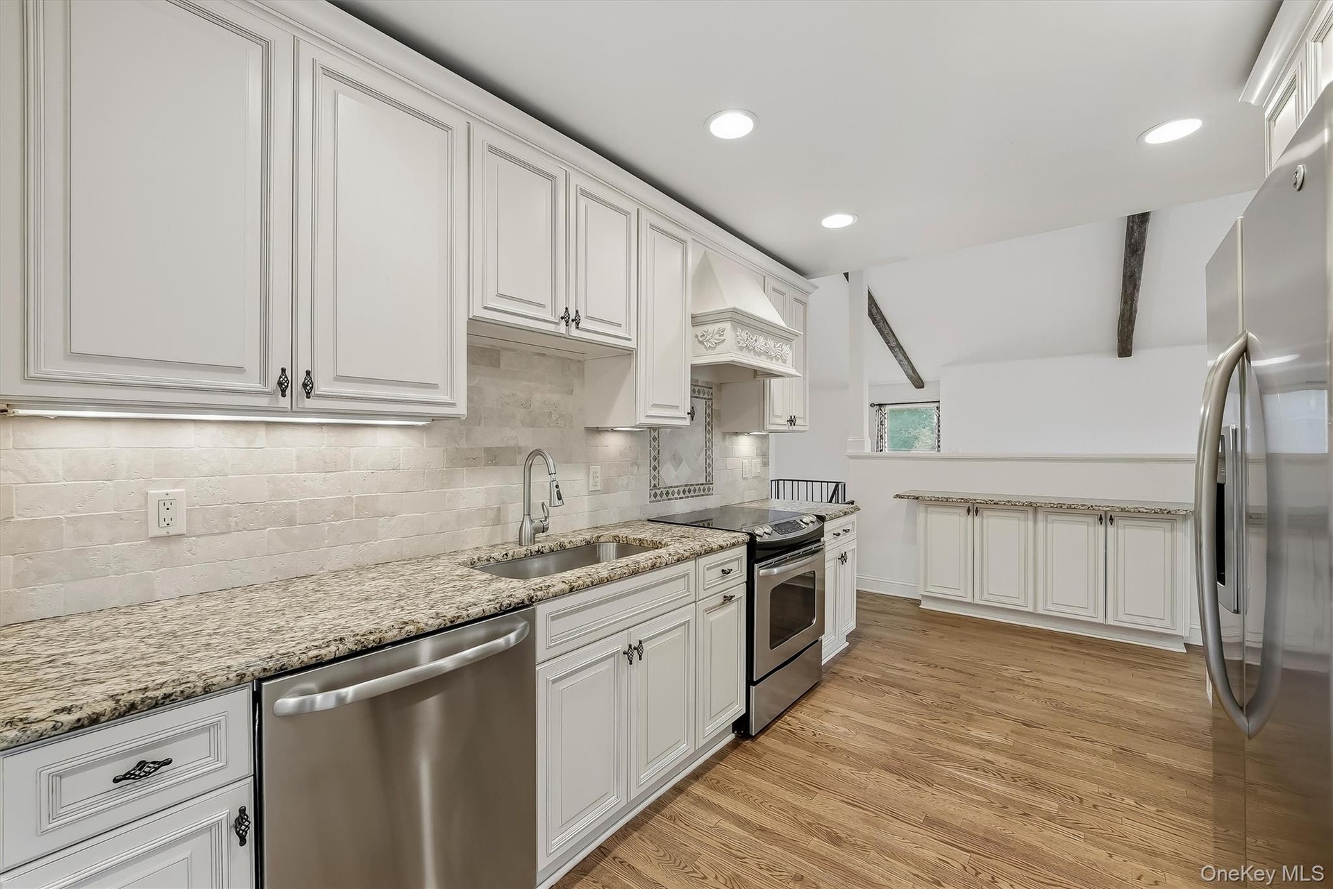Elegant white kitchen w/ pantry, granite countertops, & custom cabinetry.