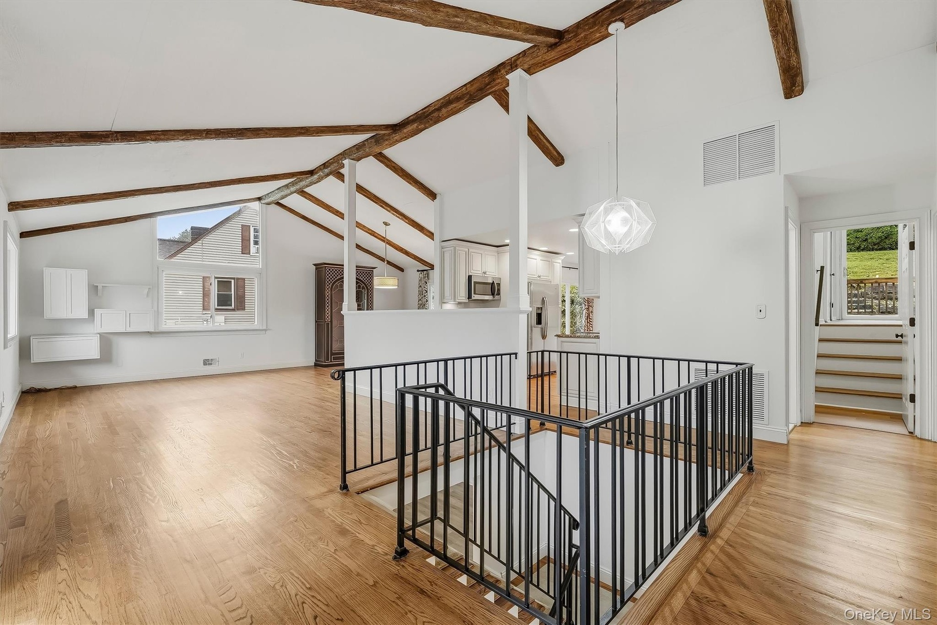 Open-plan great room w/ hardwood floors, exposed wood beams, and fresh paint.