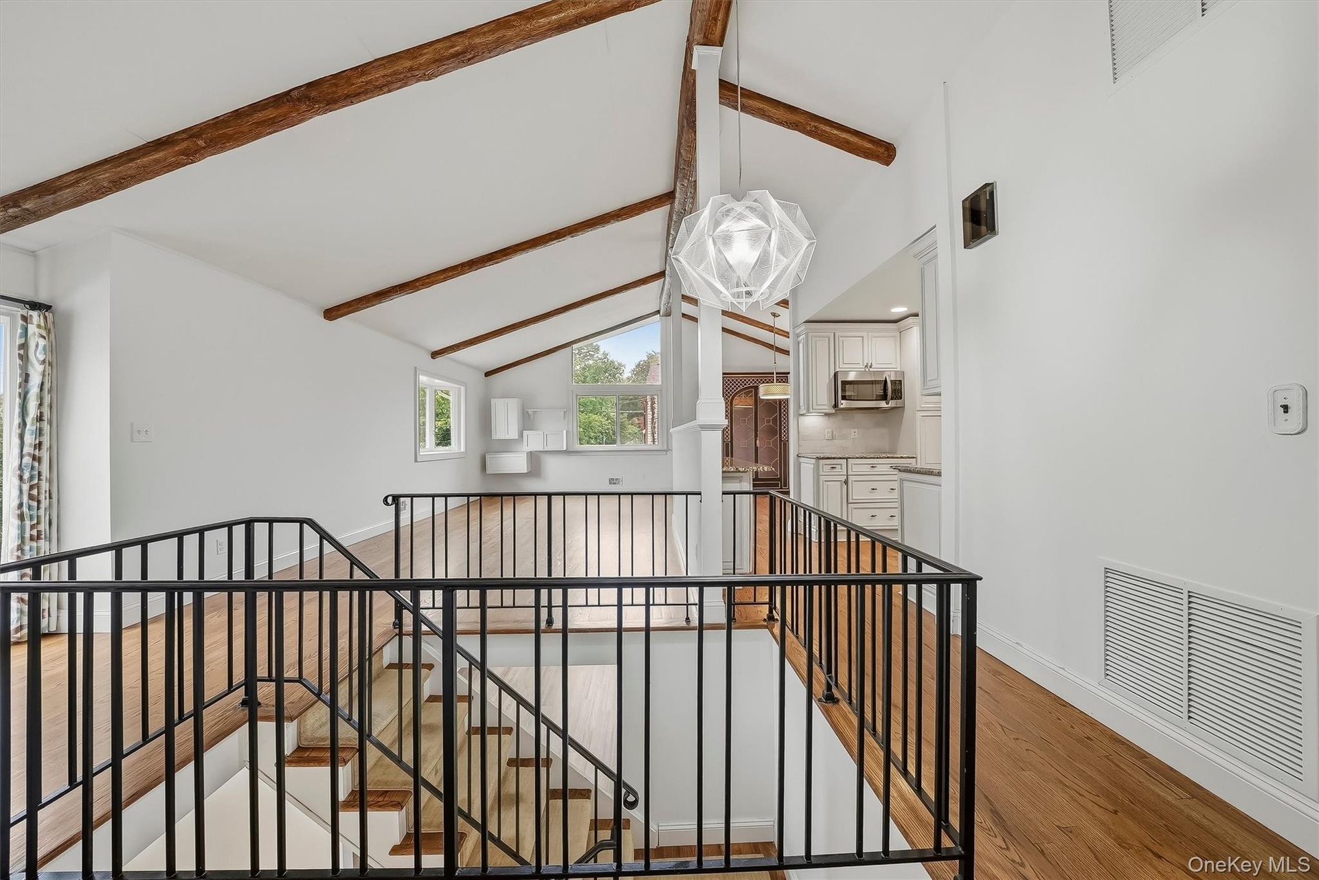Open-plan great room w/ hardwood floors, exposed wood beams, and fresh paint.