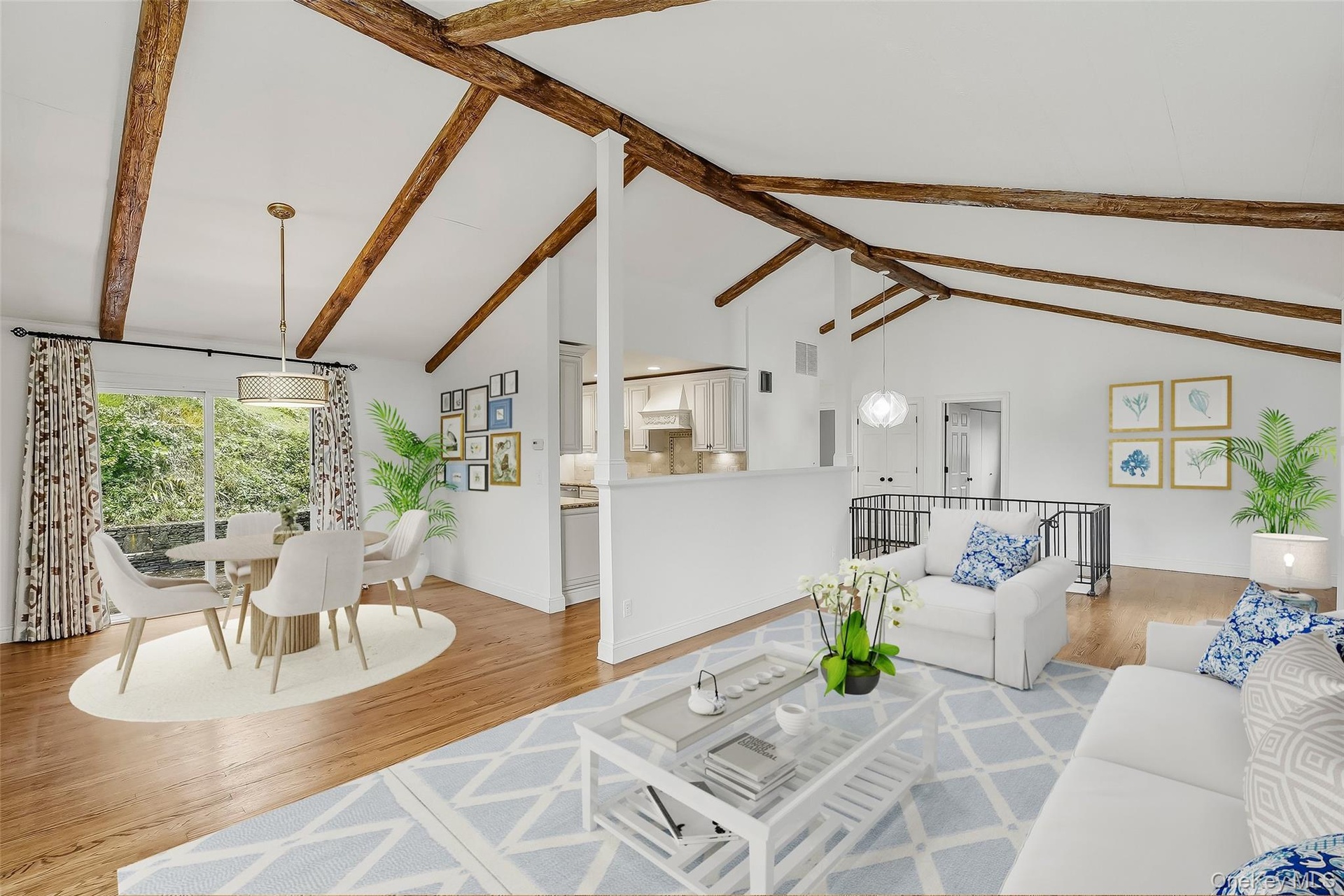 Virtually staged open-plan great room w/ hardwood floors, exposed wood beams, and fresh paint.
