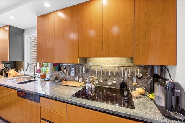 Wood-finish cabinetry paired with a built-in cooktop, undermount sink, and recessed lighting