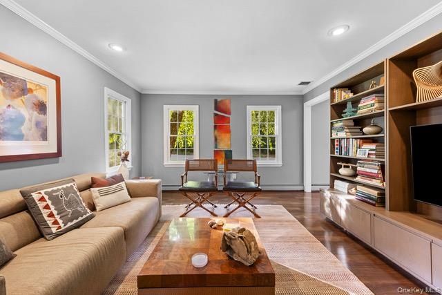 Sophisticated living room showcasing hardwood flooring, recessed ceiling lighting, and expansive windows framing natural light