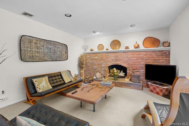 Brick-faced fireplace with an arched opening, recessed lighting, and light-colored carpeting