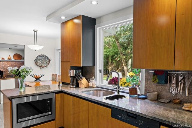 Wood-finish cabinetry paired with stone countertops and a stainless steel under-counter microwave