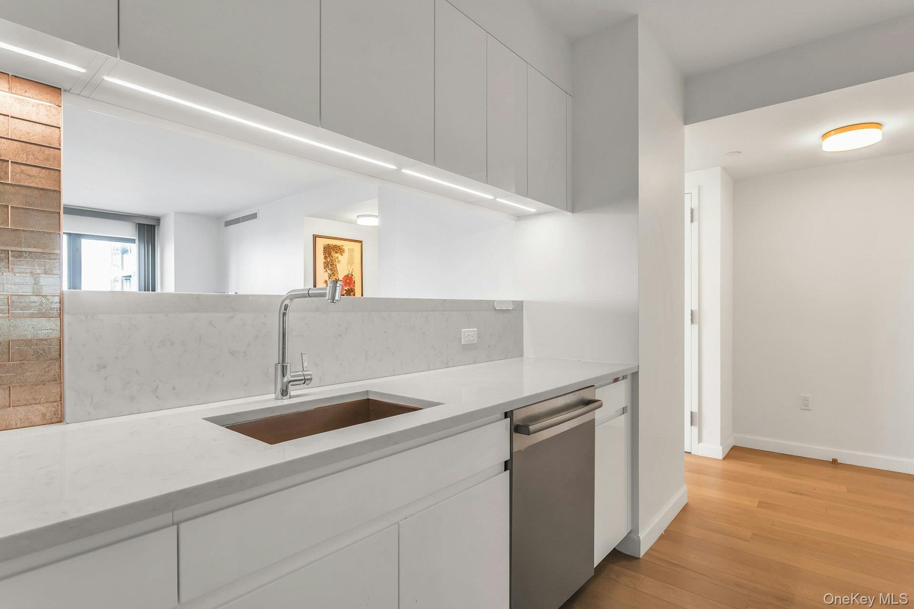 Kitchen featuring stainless steel dishwasher, light stone countertops, white cabinetry, light wood-style flooring, and modern cabinets