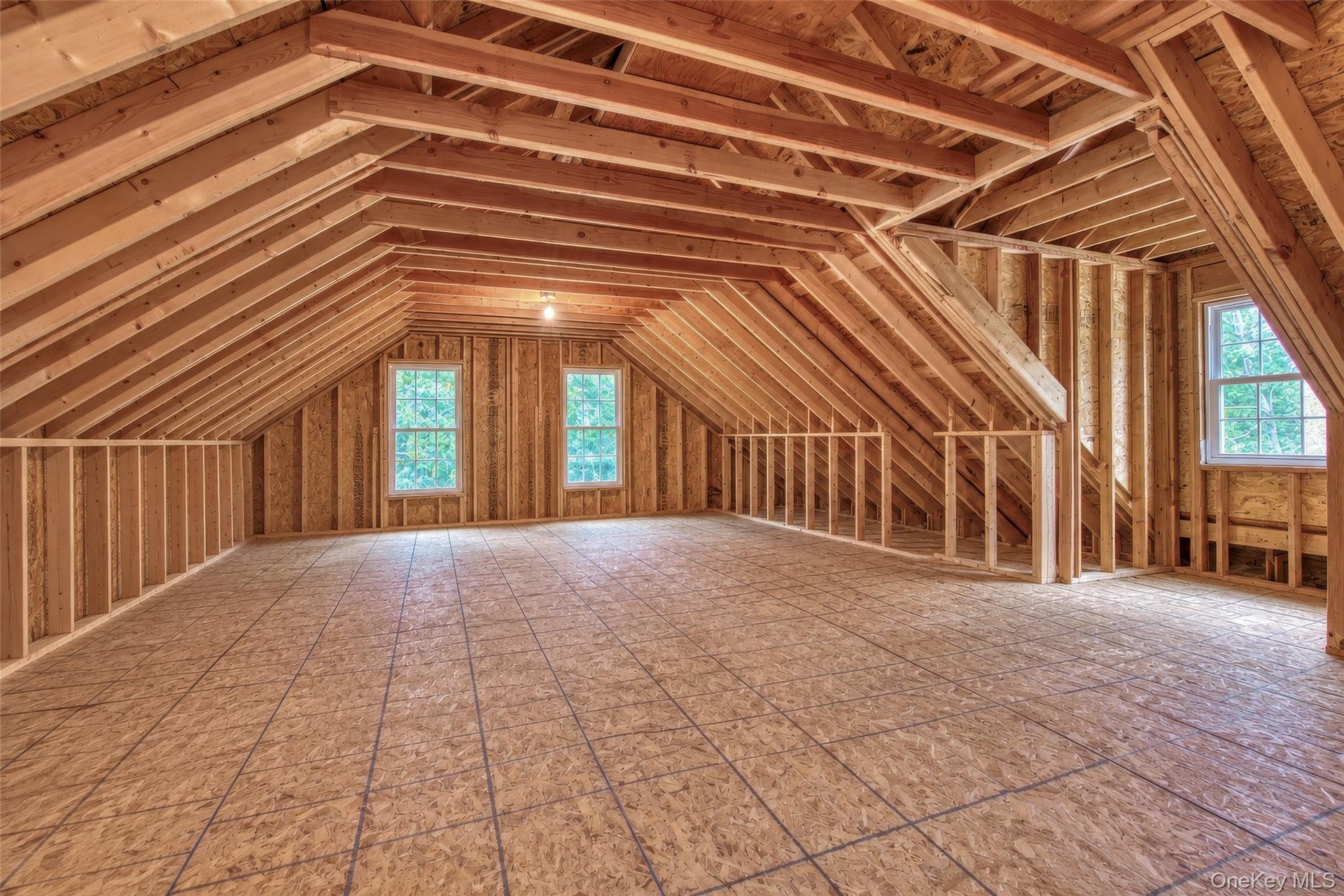 Expansive unfinished 2nd floor area featuring exposed wood framing, wood subflooring, and multiple windows
