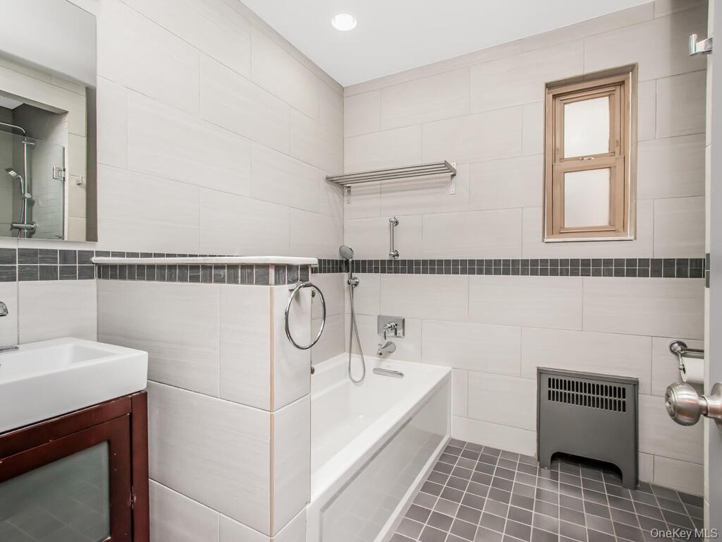 Bathroom featuring vanity, tile walls, radiator, and tile patterned floors