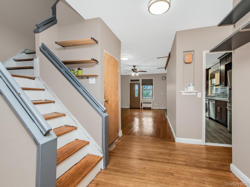 Foyer entrance featuring stairway, baseboards, light wood-style floors, and ceiling fan