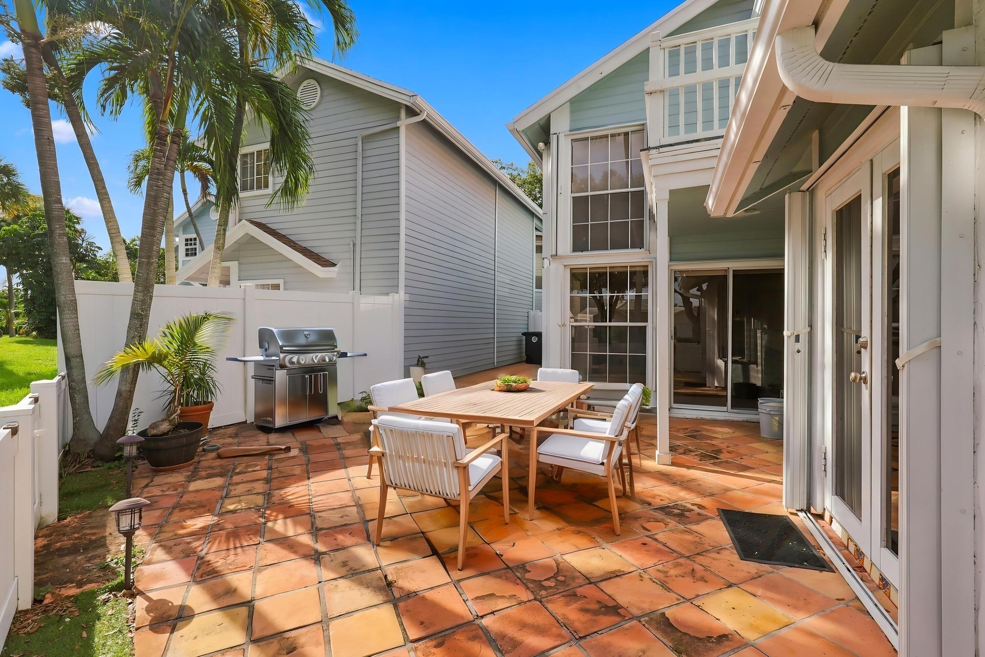 The private backyard is designed for effortless Florida living, featuring an expansive Spanish tile patio with a covered area for year-round enjoyment
