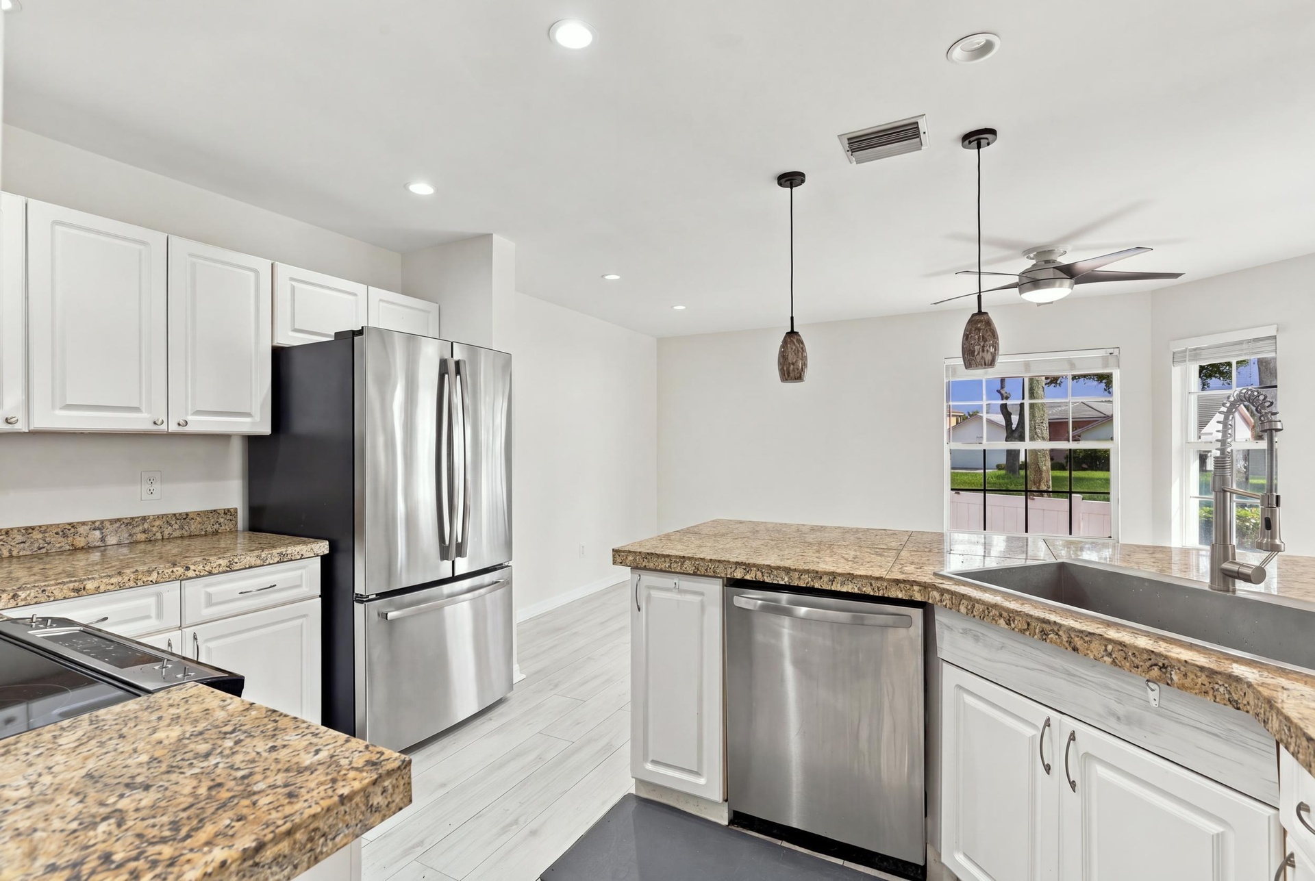 The bright eat-in kitchen features contemporary white cabinetry, granite countertops, new stainless steel appliances, and a convenient breakfast bar. 