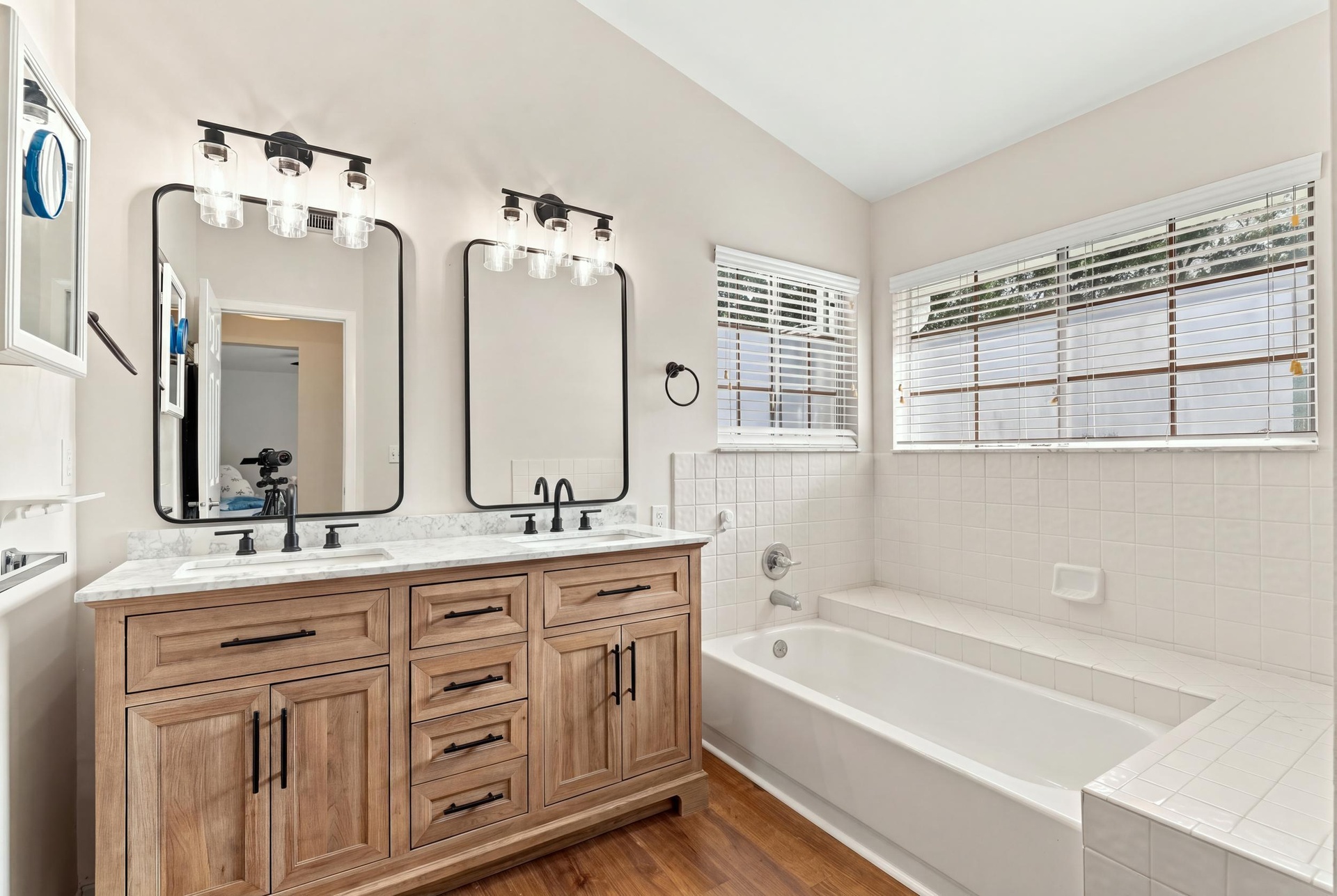 The fully updated primary ensuite exudes refined elegance with a natural oak vanity, quartz countertops, new fixtures, a relaxing bathtub, and a beaut