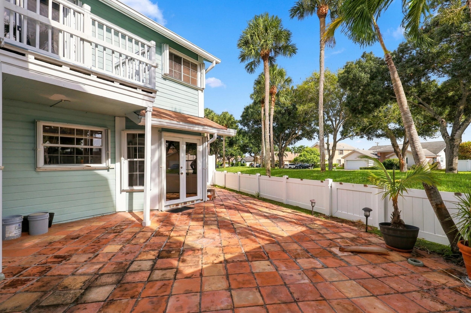 The private backyard is designed for effortless Florida living, featuring an expansive Spanish tile patio with a covered area for year-round enjoyment