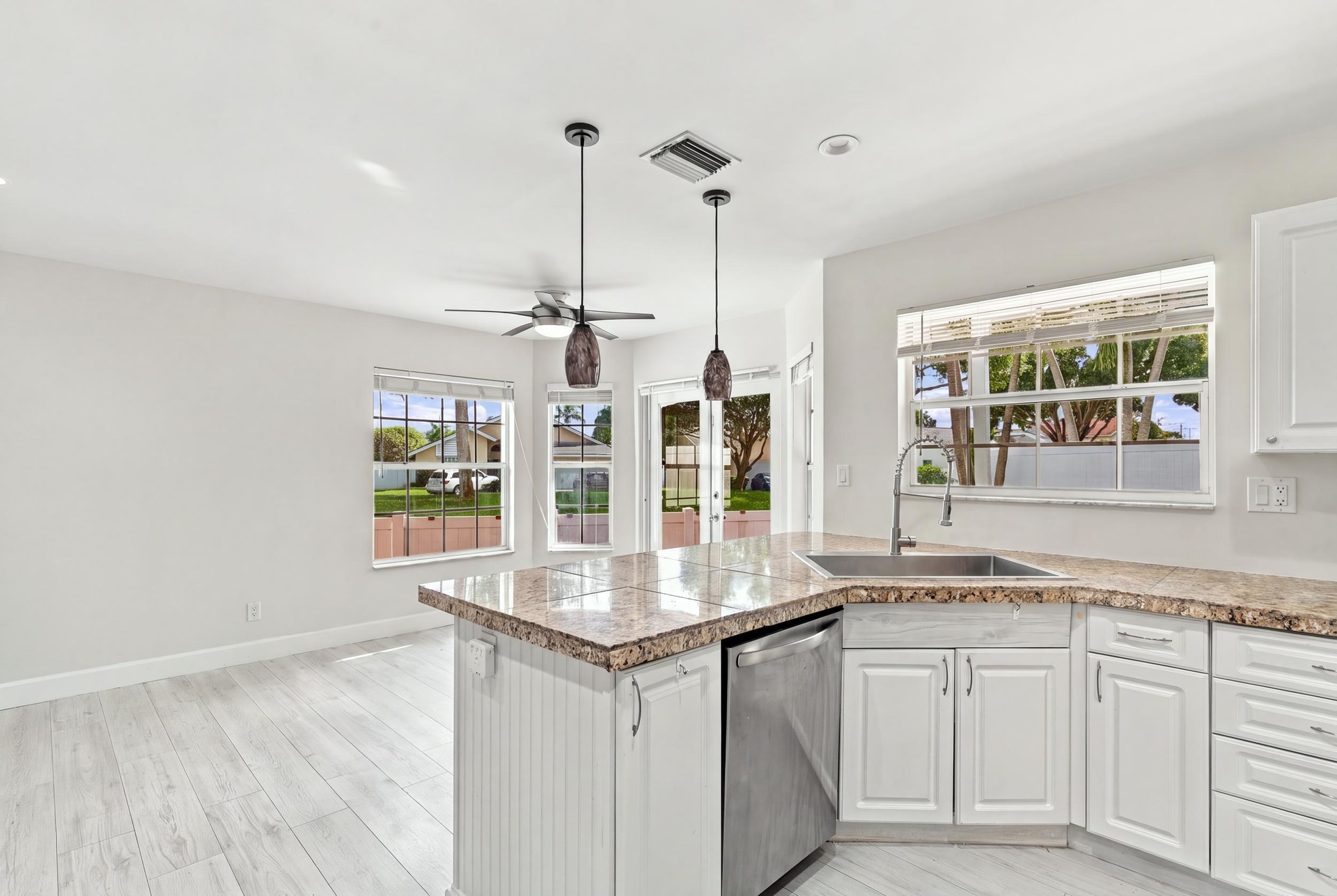 The bright eat-in kitchen features contemporary white cabinetry, granite countertops, new stainless steel appliances, and a convenient breakfast bar. 