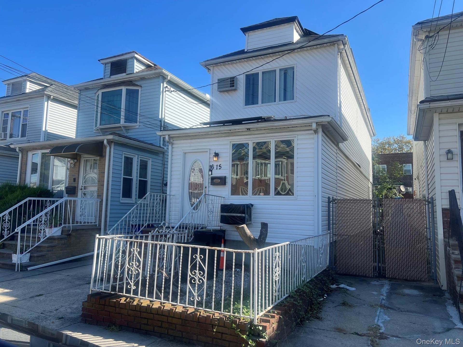 White vinyl siding exterior with an arched entry door and decorative front fencing