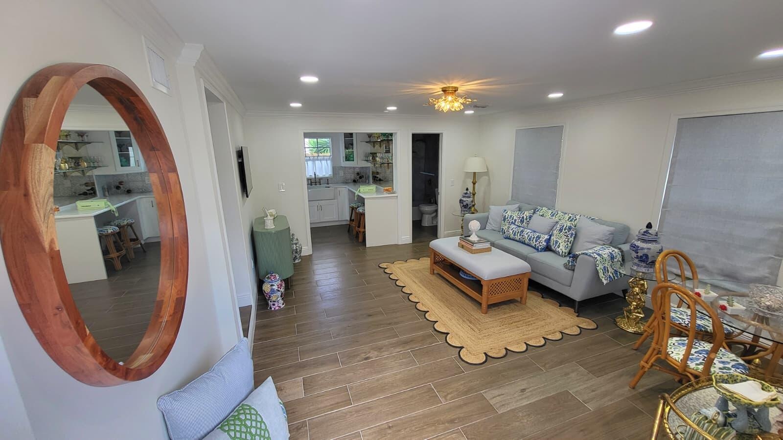Recessed lighting throughout, wood-finish flooring, and a kitchen featuring white cabinetry, a farmhouse sink, and a large island