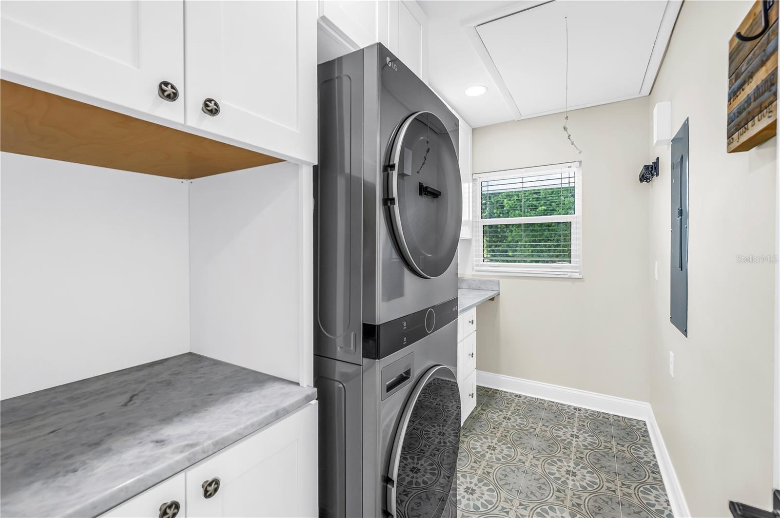 Oversized laundry room with Shaker cabinetry, quartz countertops (all match kitchen), utility sink, storage and FULL size stackable LG ThinQ high effi