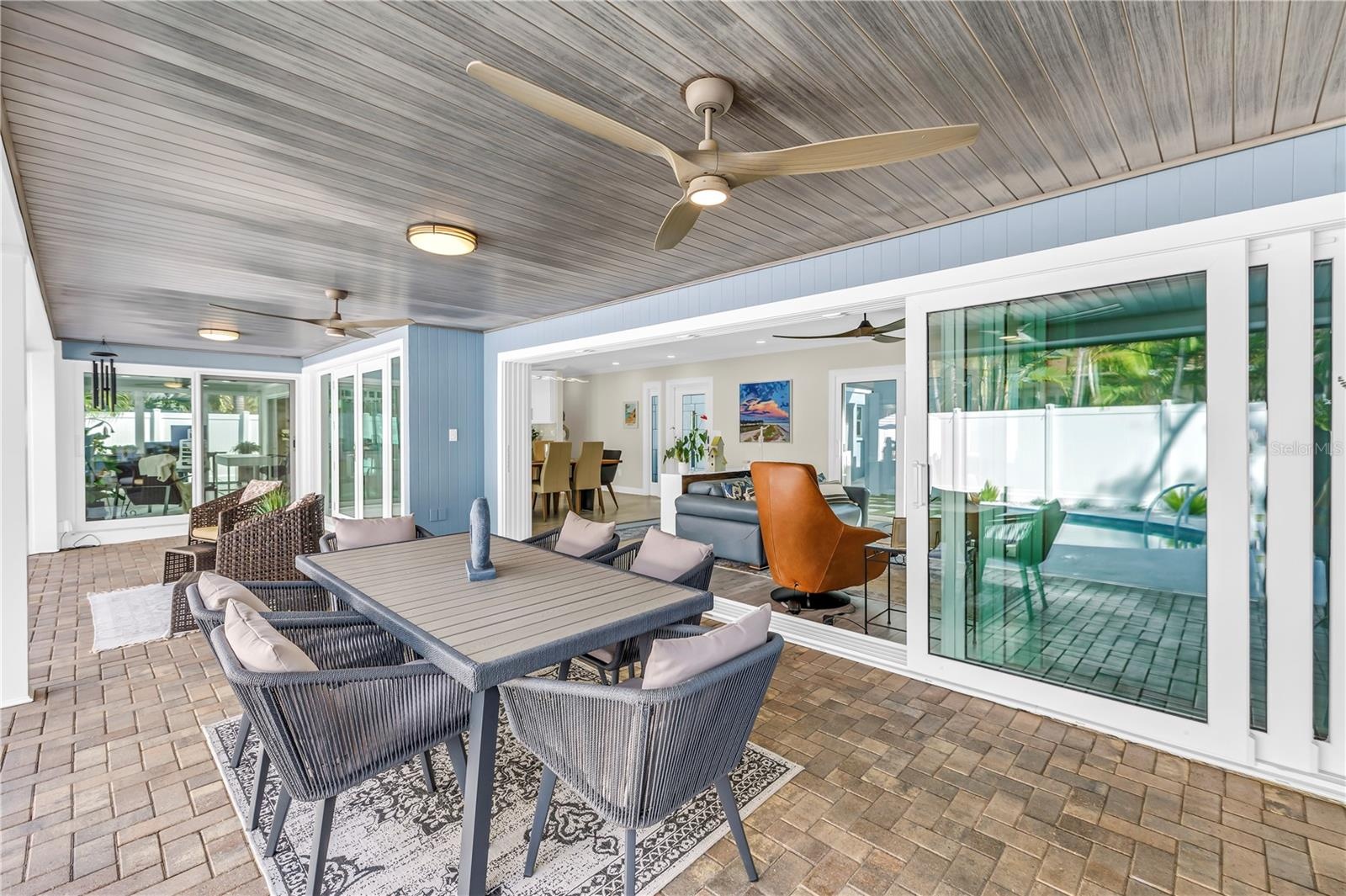 impact-rated pocket sliders disappear completely into the wall, dramatically opening the living room to the lanai and pool