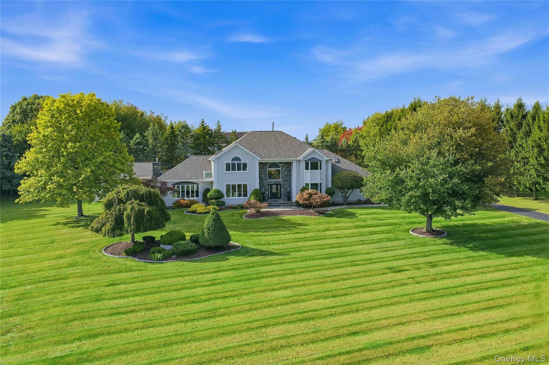 Expansive green lawn with mature trees and landscaped planting beds
