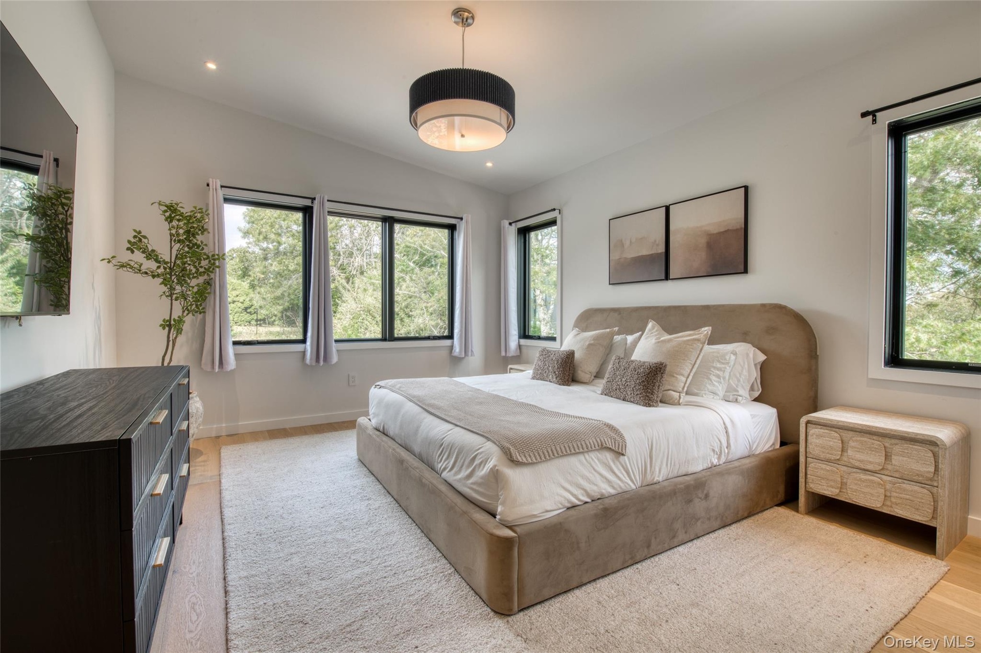 Recessed lighting, wood-finish flooring, white walls, black-framed windows, and a semi-flush mount ceiling light