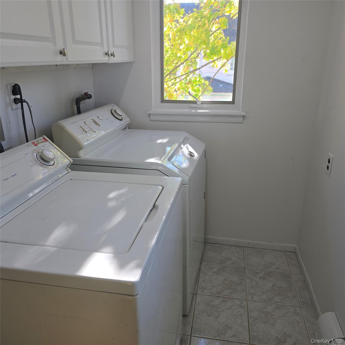Laundry room with cabinets, light tile patterned flooring, and washer and clothes dryer