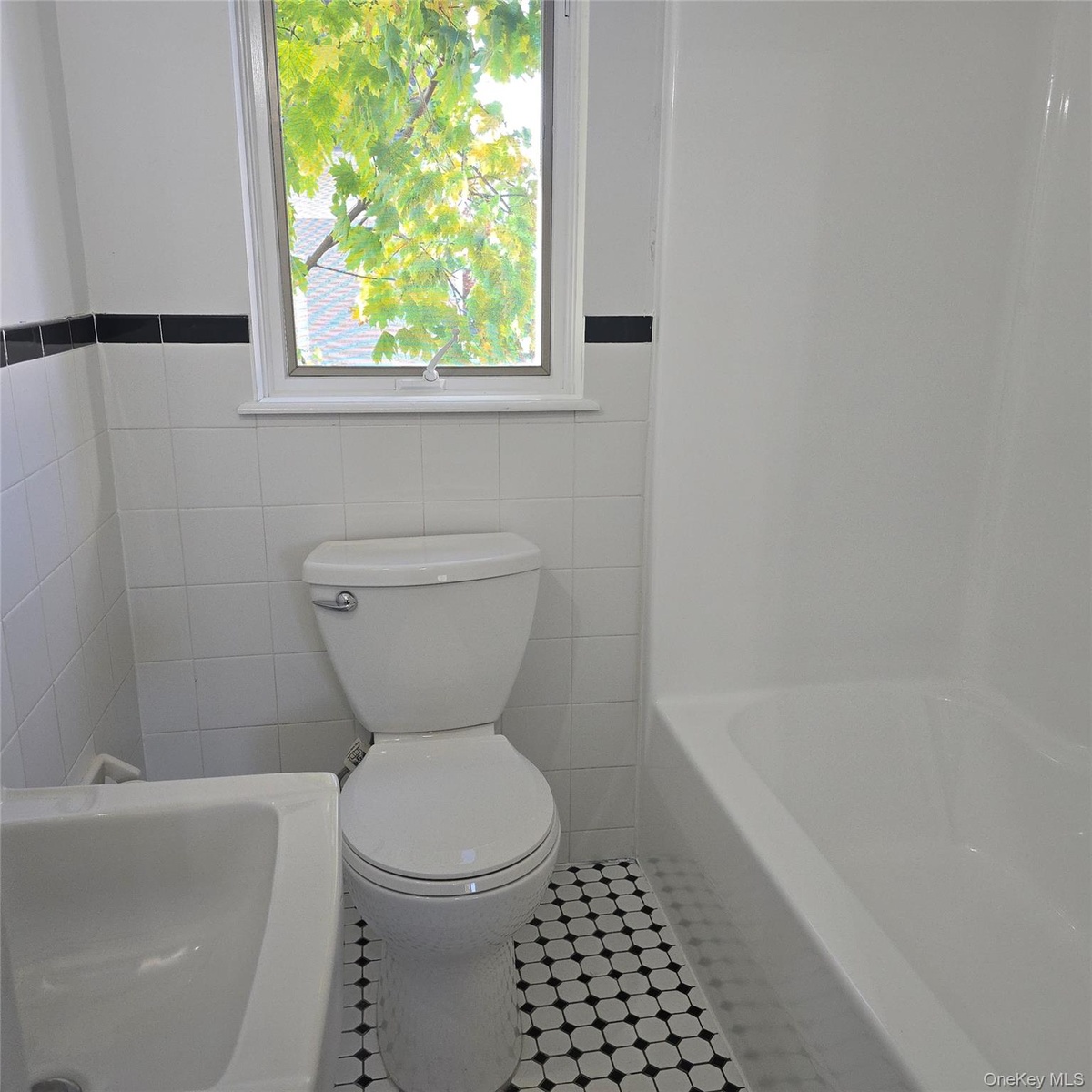 Bathroom featuring tile patterned flooring, a bathing tub, and tile walls