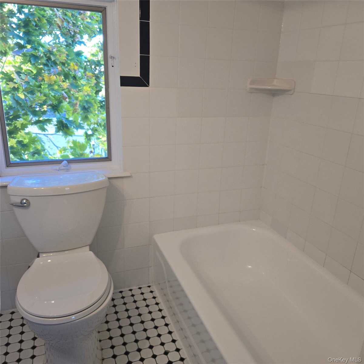 Bathroom with tile patterned floors, toilet, a tub, and tile walls