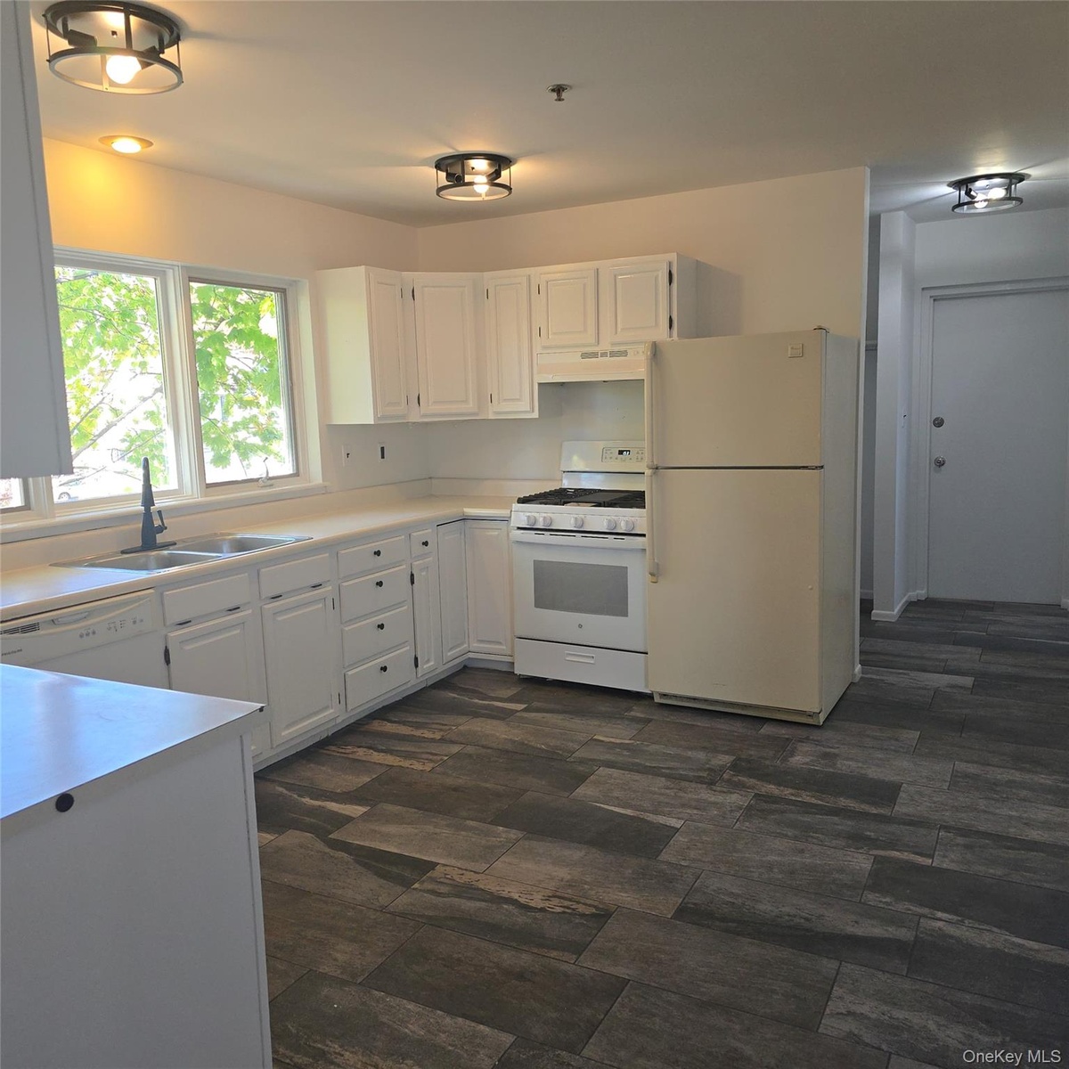 Kitchen with white appliances, white cabinetry, sink, and exhaust hood
