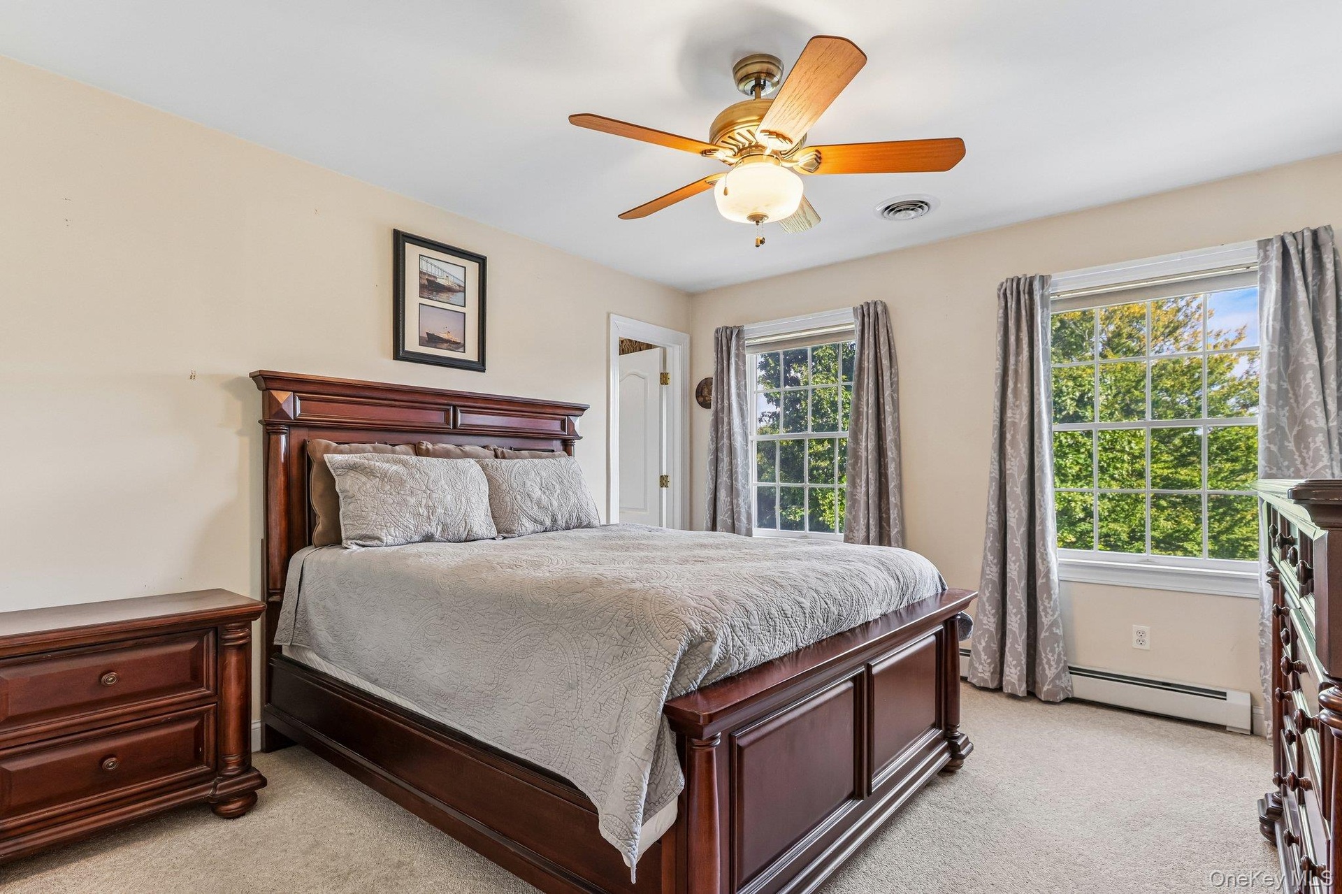 Wall-to-wall carpeting, two large windows, and a ceiling fan with integrated lighting