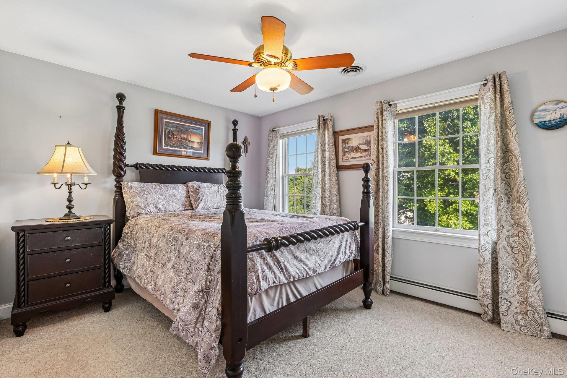 Carpeted bedroom with two large windows, a ceiling fan, and light gray wall paint