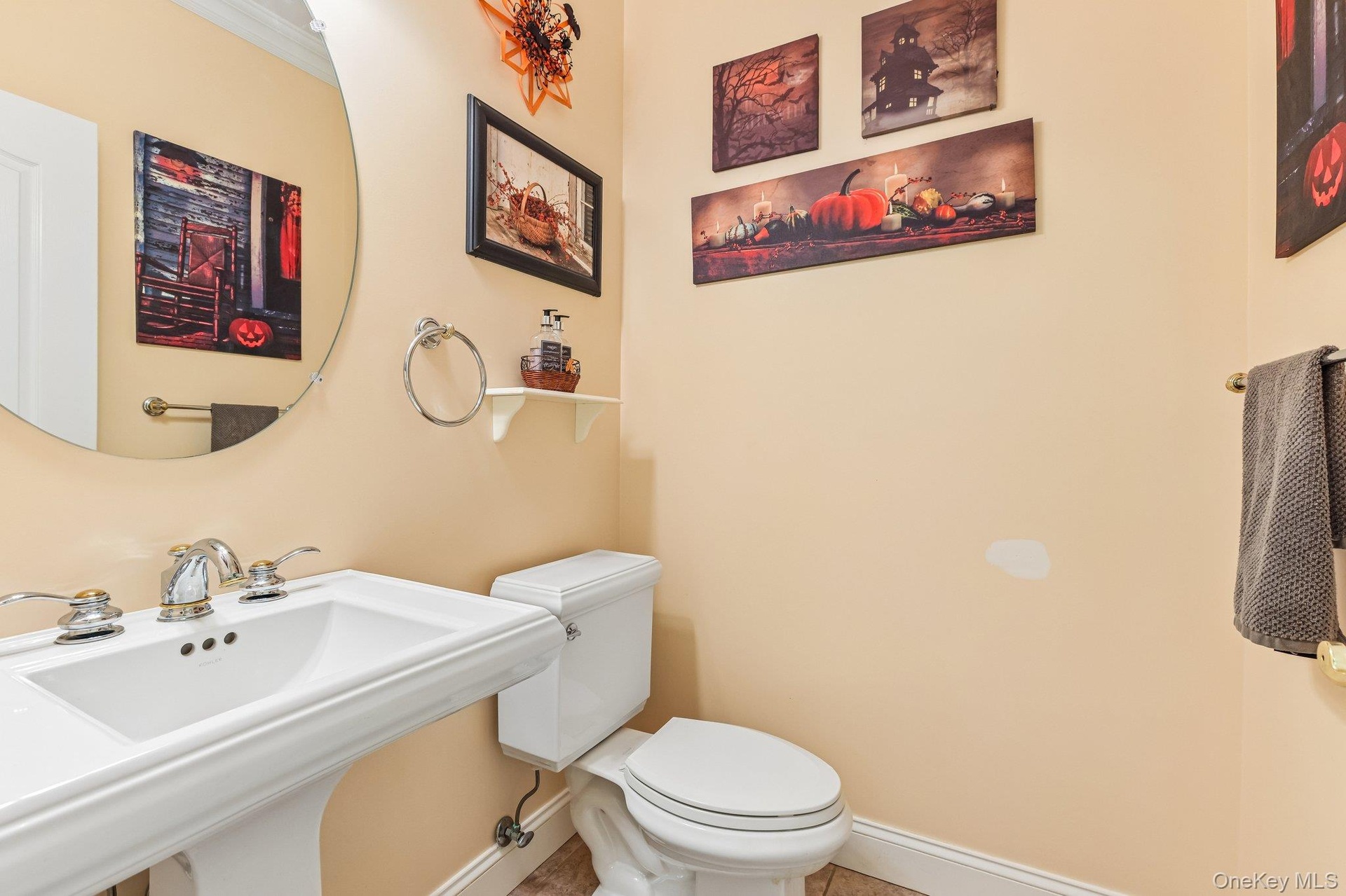 Pedestal sink with chrome fixtures, round wall-mounted mirror, and white toilet