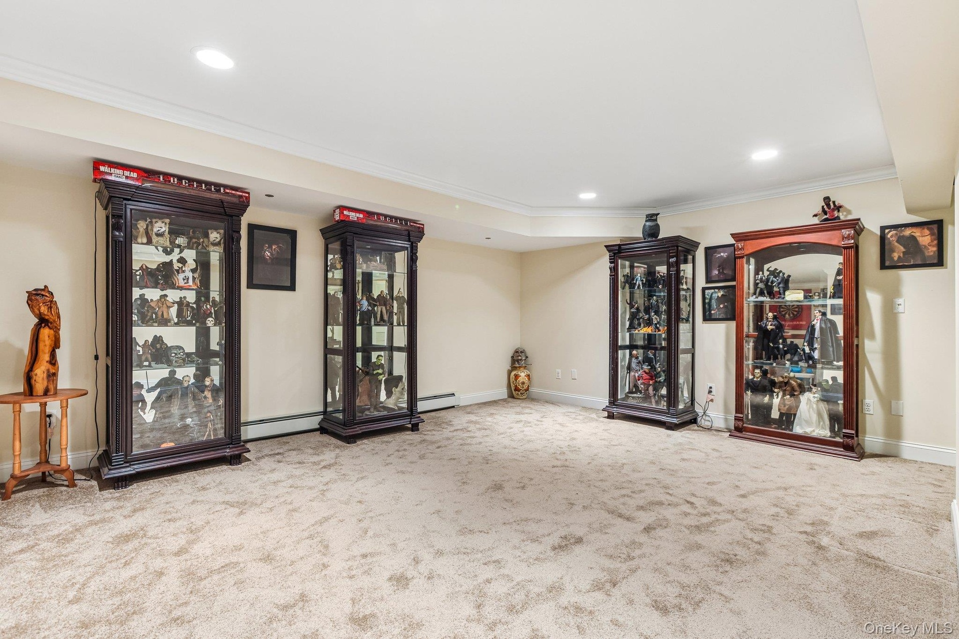 Recessed lighting, crown molding, and neutral wall tones complement the neutral carpeting