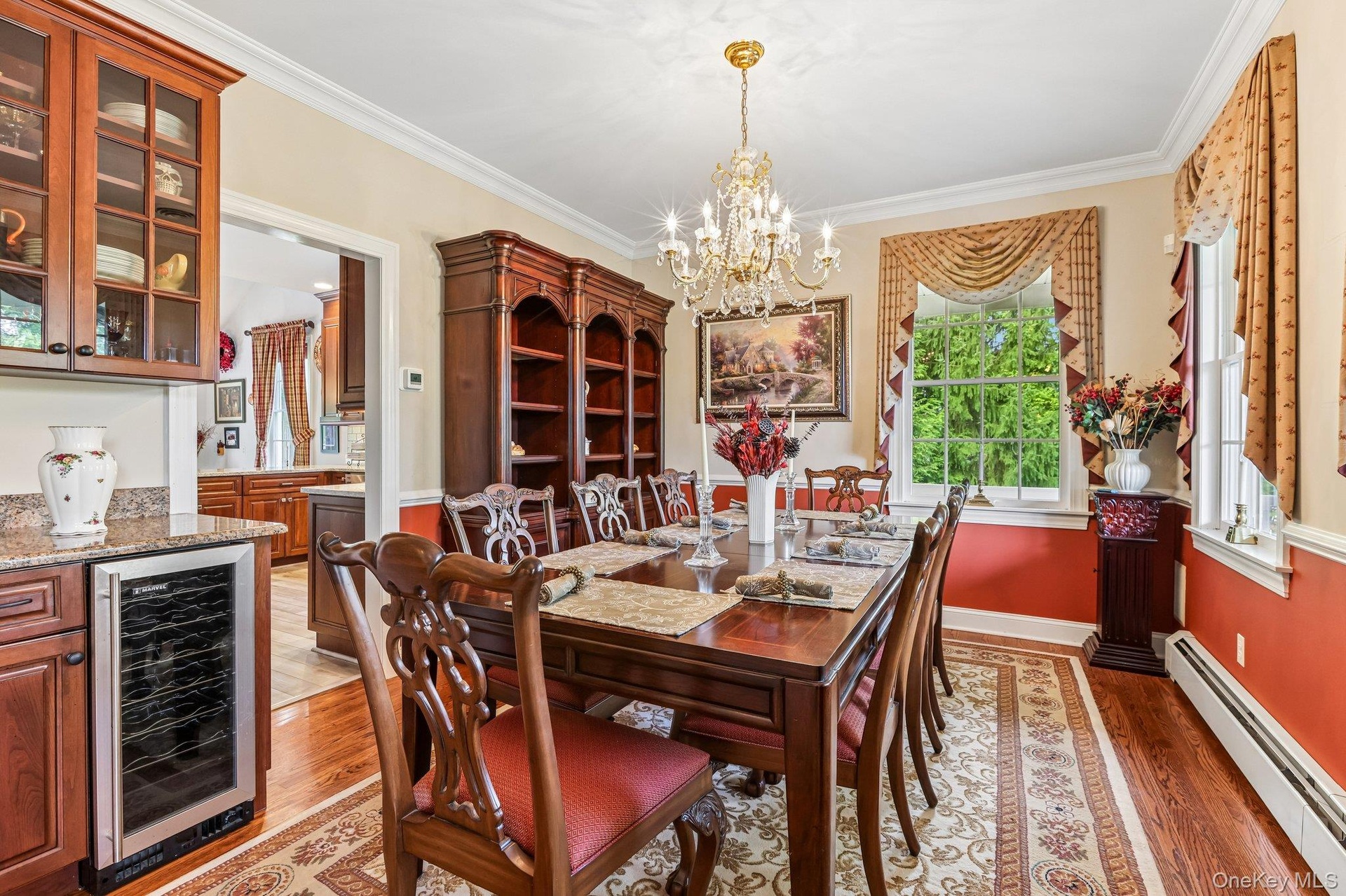 Built-in wine refrigerator, wood-finish flooring, crown molding, and a chandelier