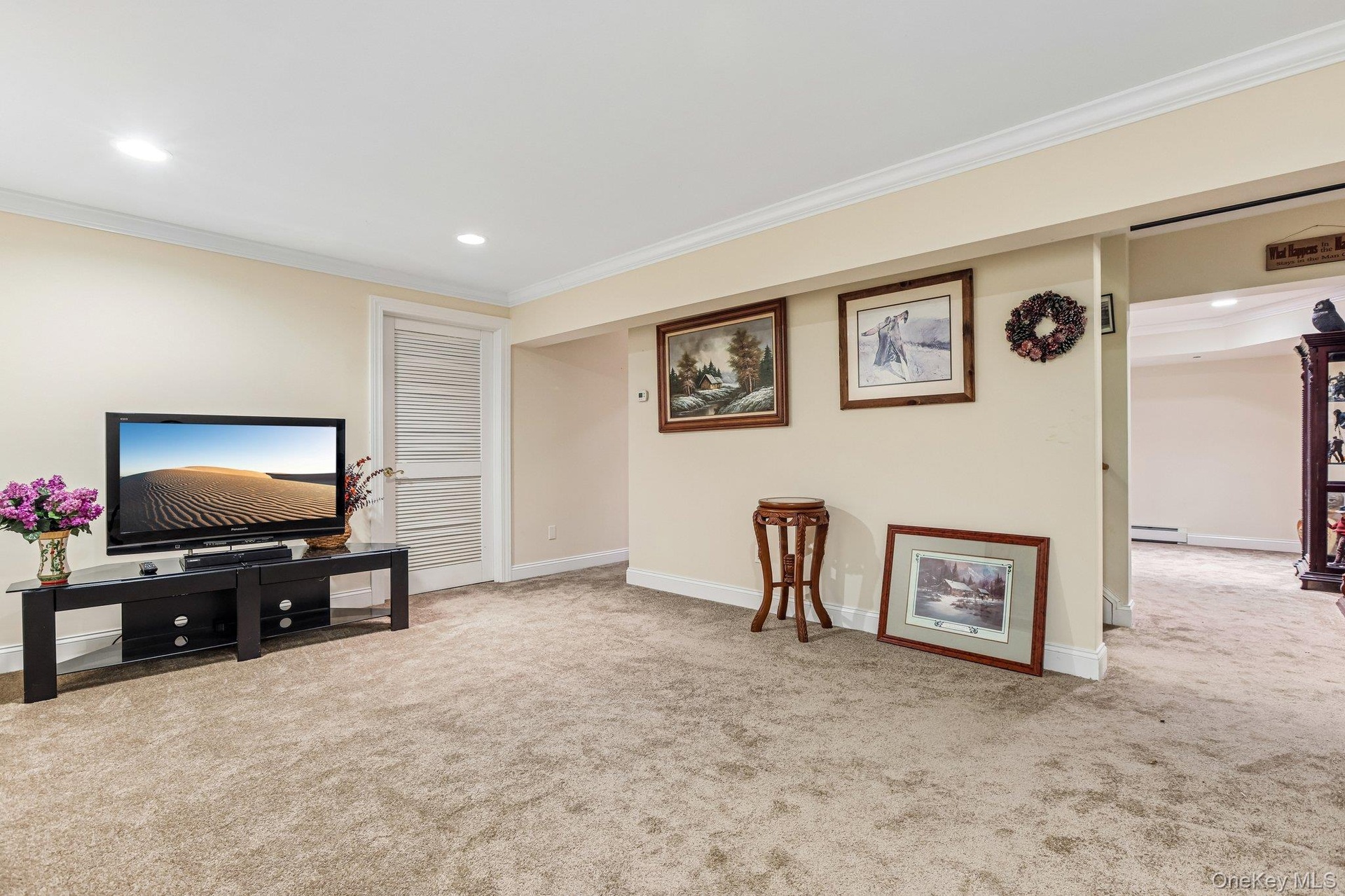Recessed lighting, crown molding, light-colored wall paint, and neutral carpeting